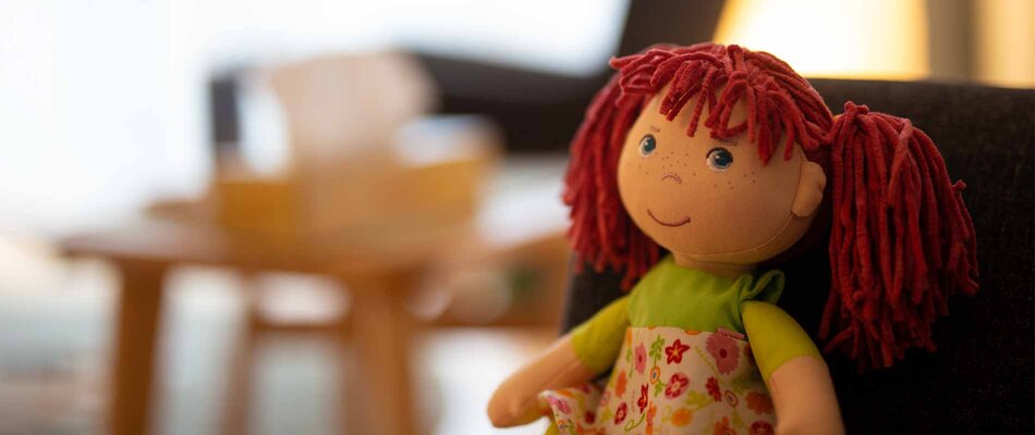Blick in die Praxis für Psychotherapie - zu sehen ist ein rothaarige Puppe mit freundlichem Gesicht